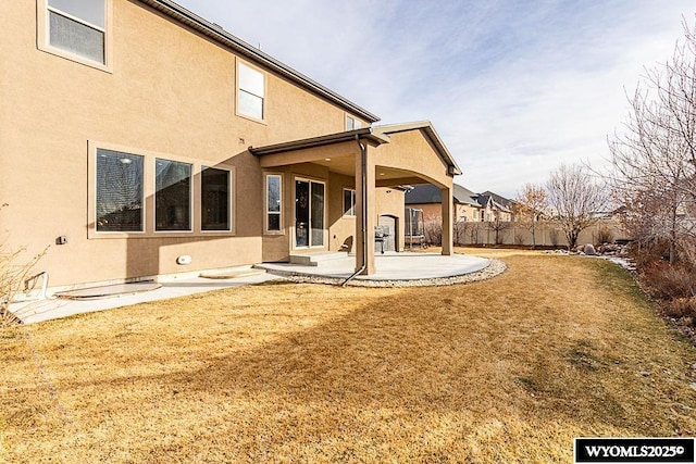 back of house with a yard and a patio