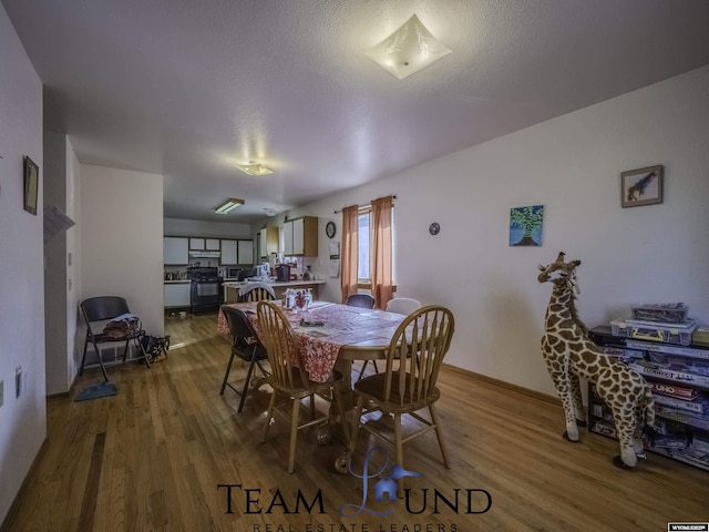 dining space with hardwood / wood-style flooring and a textured ceiling