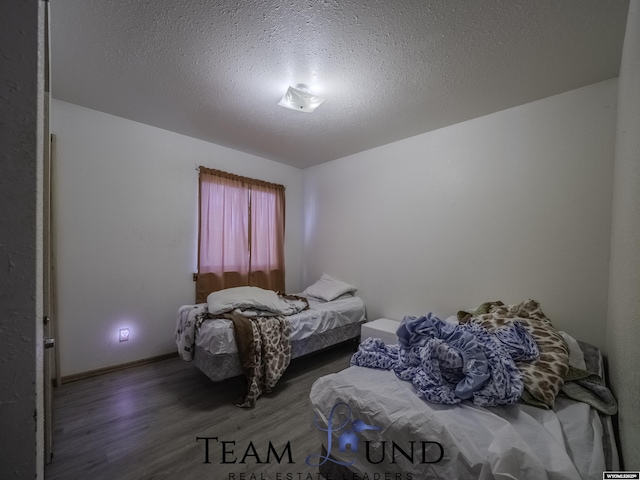 bedroom featuring dark hardwood / wood-style flooring and a textured ceiling