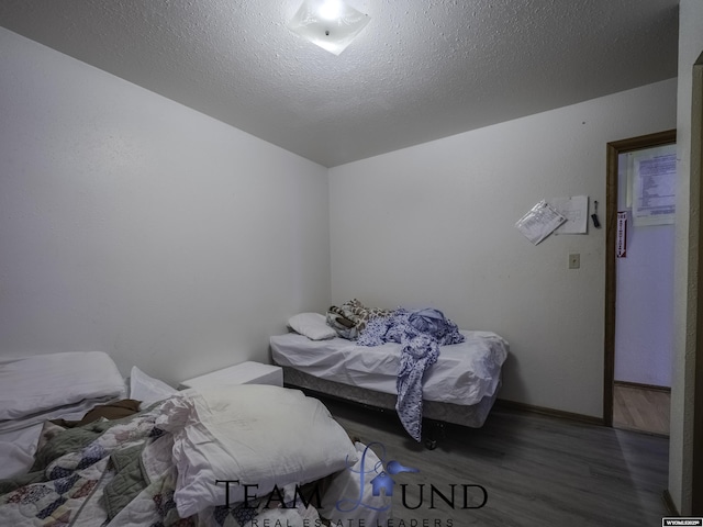 bedroom with dark wood-type flooring and a textured ceiling