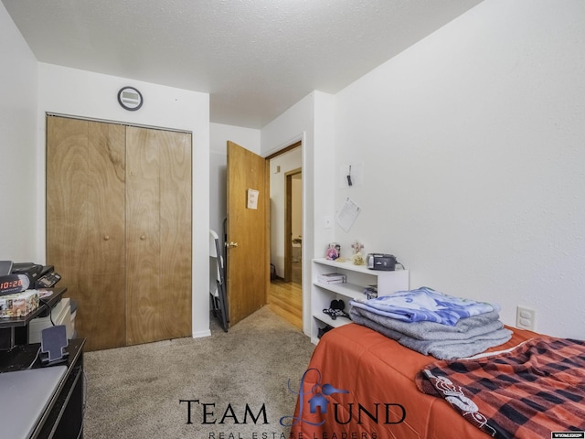 bedroom featuring light colored carpet, a textured ceiling, and a closet