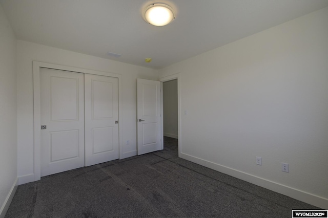 unfurnished bedroom featuring a closet and dark colored carpet