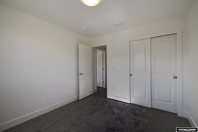 unfurnished bedroom featuring dark carpet and a closet