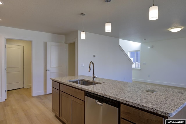 kitchen featuring sink, dishwasher, an island with sink, pendant lighting, and light stone countertops