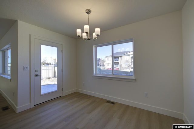 unfurnished dining area featuring a chandelier and light wood-type flooring