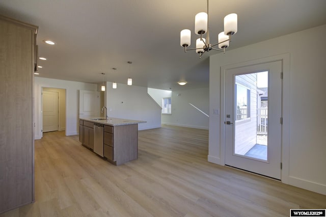 kitchen with pendant lighting, sink, light hardwood / wood-style flooring, light stone counters, and stainless steel dishwasher