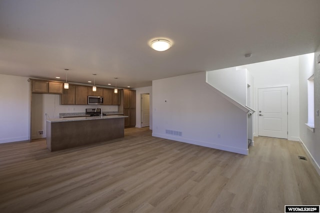 kitchen featuring hardwood / wood-style floors, decorative light fixtures, an island with sink, sink, and stainless steel appliances