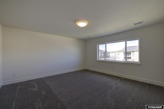 carpeted empty room featuring a textured ceiling