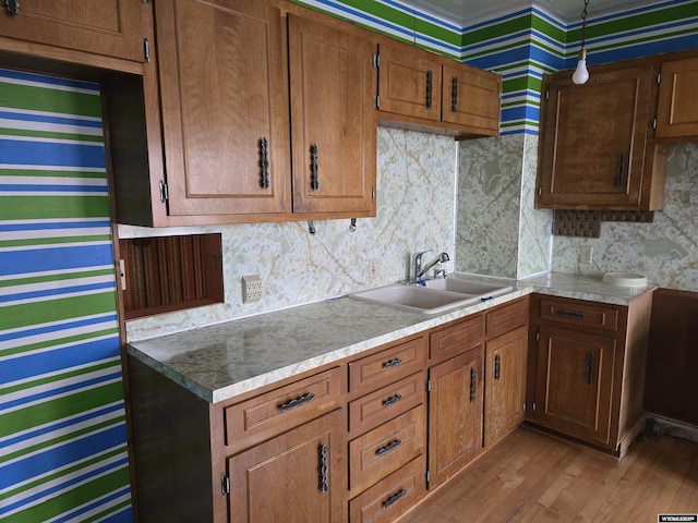 kitchen with decorative light fixtures, light hardwood / wood-style floors, sink, and decorative backsplash