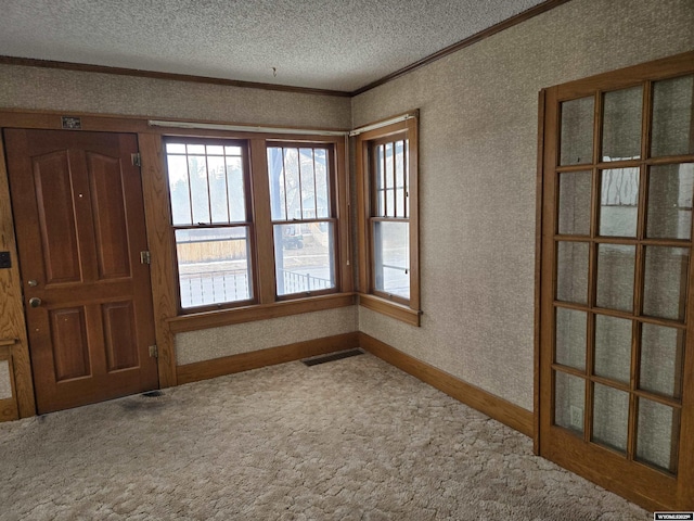 carpeted empty room featuring crown molding and a textured ceiling