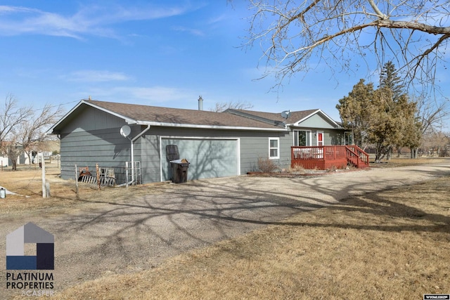 rear view of house featuring a wooden deck and a garage