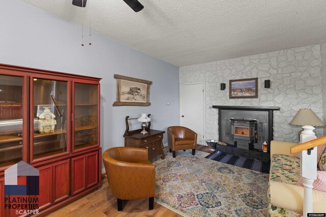 living room with ceiling fan, light hardwood / wood-style floors, and a textured ceiling