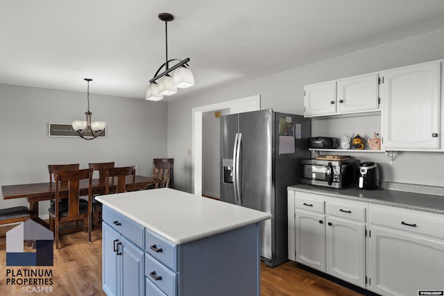 kitchen featuring dark wood-type flooring, blue cabinetry, hanging light fixtures, stainless steel appliances, and white cabinets