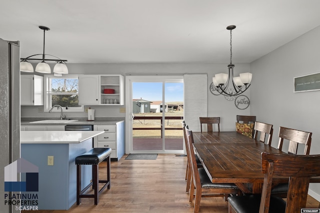 dining space with plenty of natural light, sink, a chandelier, and light wood-type flooring