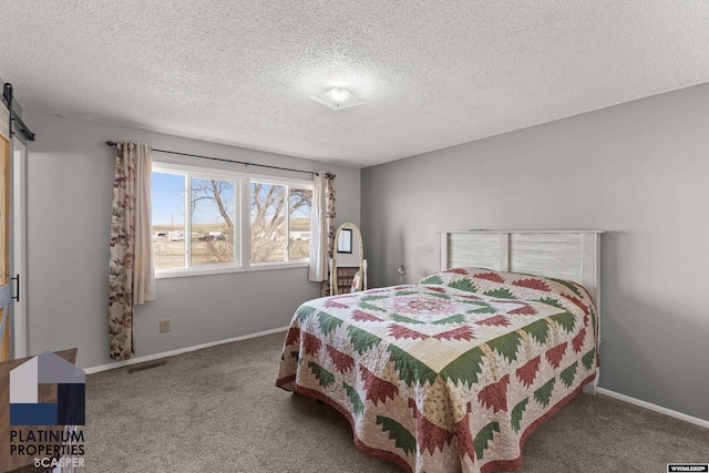 carpeted bedroom with a barn door and a textured ceiling