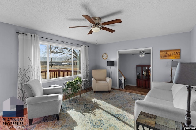 living room with ceiling fan, dark wood-type flooring, and a textured ceiling