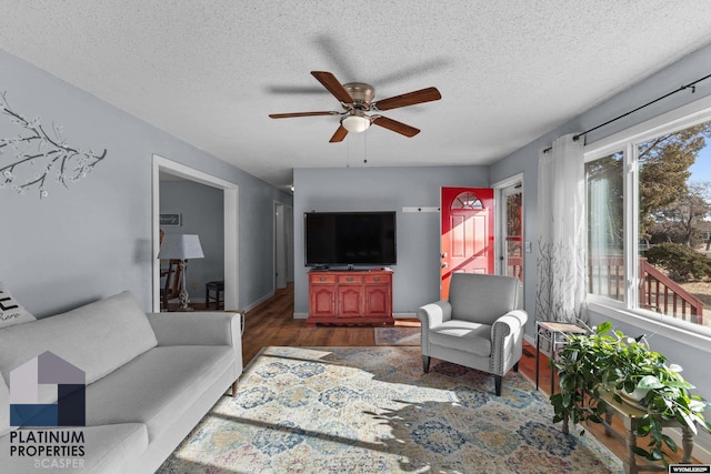 living room featuring ceiling fan, a textured ceiling, and dark hardwood / wood-style flooring