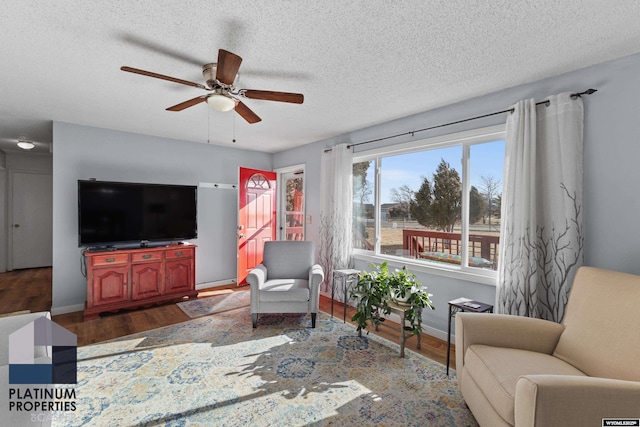 living room featuring ceiling fan, a textured ceiling, and dark hardwood / wood-style flooring