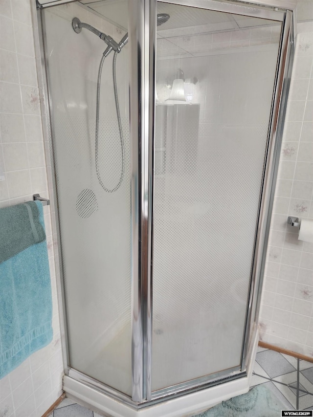 full bathroom with tile patterned flooring and a shower stall