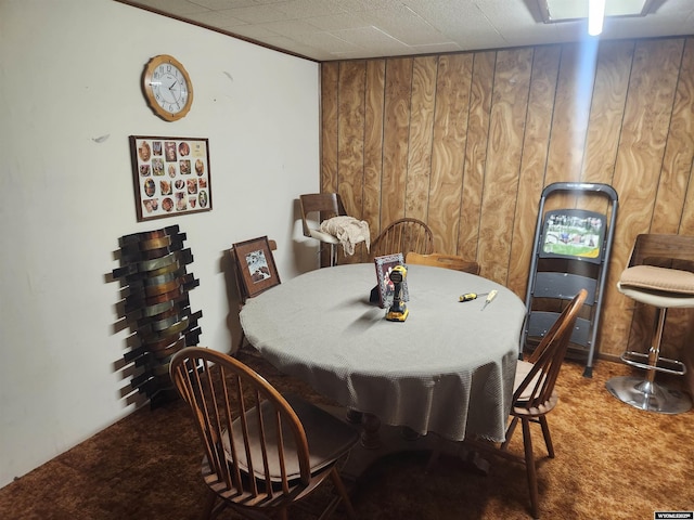 dining room featuring carpet and wooden walls