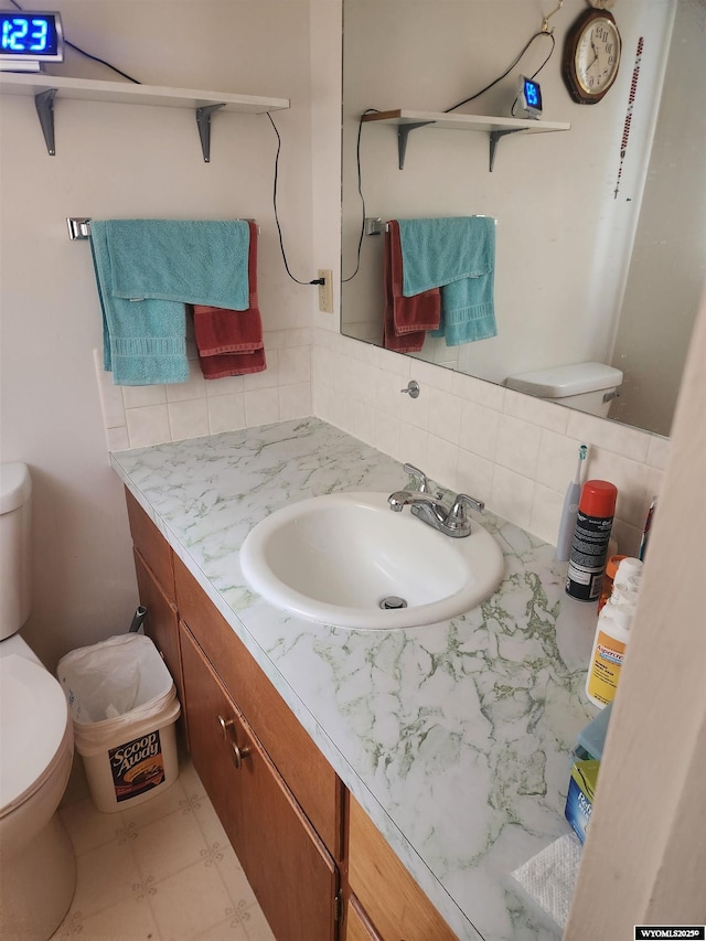 bathroom with toilet, vanity, decorative backsplash, and tile patterned floors