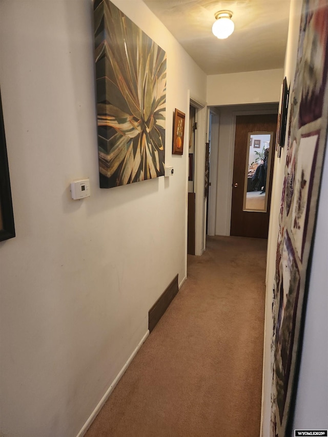 hallway with carpet floors and baseboards