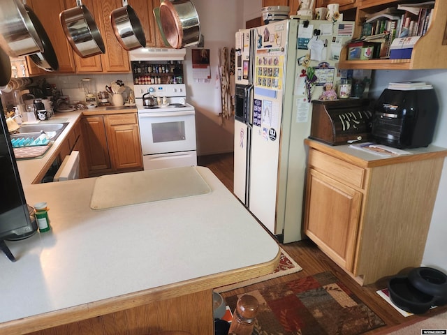 kitchen featuring light countertops, white appliances, dark wood-type flooring, and a peninsula