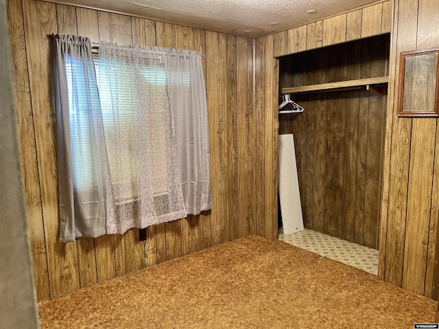 unfurnished bedroom featuring wooden walls, a closet, and carpet flooring