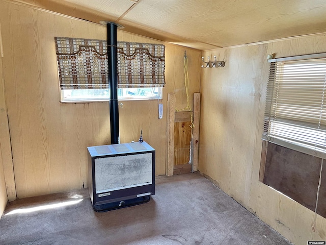 unfurnished living room with carpet, a wood stove, and wood walls