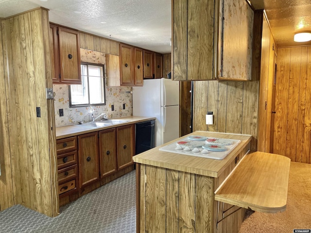 kitchen with sink, white appliances, a textured ceiling, and wood walls