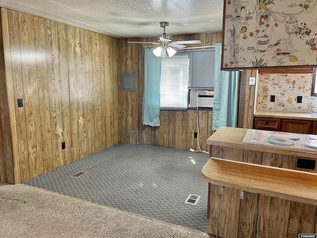 kitchen featuring carpet floors, wooden walls, and ceiling fan