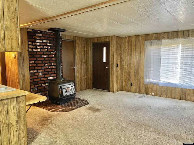 living room with carpet floors, a wood stove, and wood walls