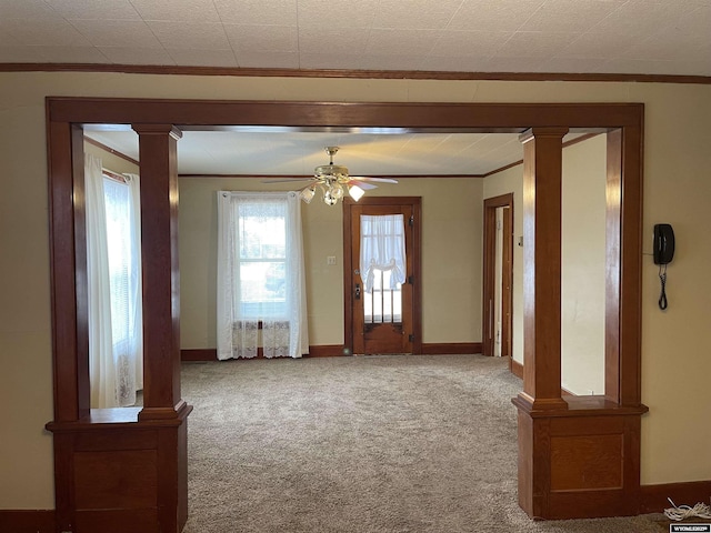 carpeted spare room with decorative columns, ornamental molding, and ceiling fan