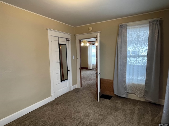 empty room with crown molding and dark carpet