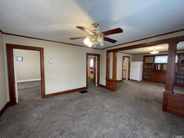 unfurnished living room with ornate columns, ornamental molding, ceiling fan, and dark carpet