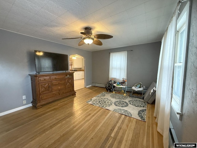 living area with ceiling fan, a baseboard radiator, and light hardwood / wood-style flooring