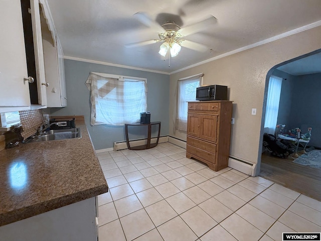 kitchen with sink, light tile patterned floors, ornamental molding, ceiling fan, and a baseboard heating unit