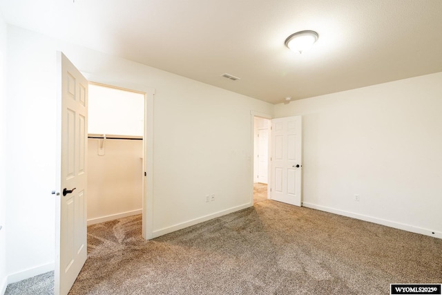 unfurnished bedroom with a walk in closet and carpet floors