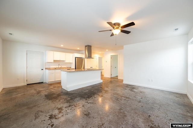 kitchen featuring a kitchen island, island range hood, white cabinetry, sink, and stainless steel fridge