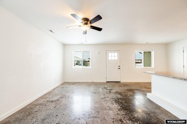 unfurnished living room with ceiling fan and concrete floors