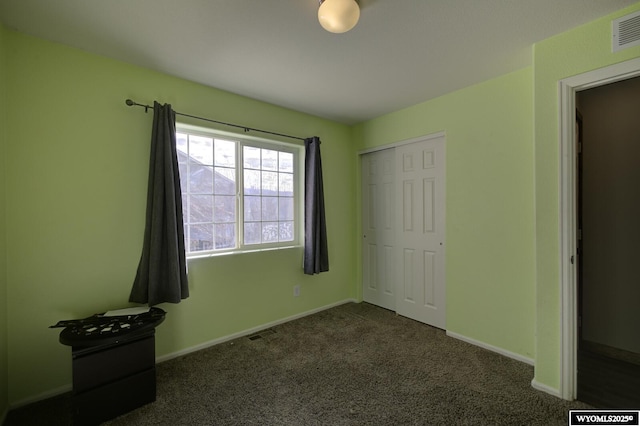 unfurnished bedroom featuring dark carpet and a closet