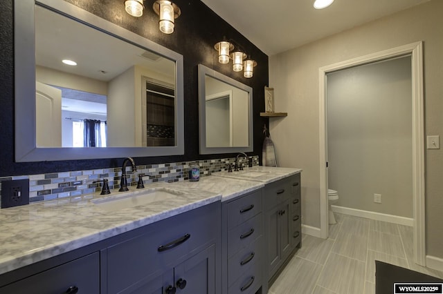 bathroom featuring vanity, toilet, and backsplash