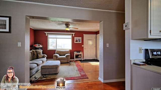 living room featuring hardwood / wood-style flooring, ceiling fan, and a textured ceiling