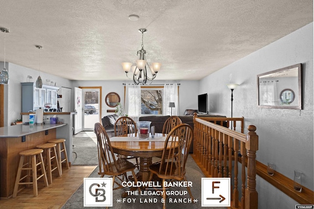 dining area with a chandelier, light hardwood / wood-style flooring, and a textured ceiling