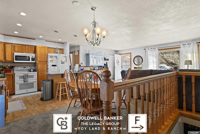 dining area with a notable chandelier, light hardwood / wood-style floors, and a textured ceiling