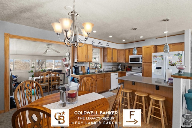 kitchen with ceiling fan with notable chandelier, white appliances, a healthy amount of sunlight, and sink