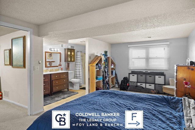 carpeted bedroom featuring connected bathroom and a textured ceiling