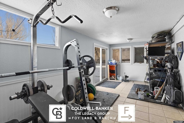 workout area featuring light tile patterned floors and a textured ceiling