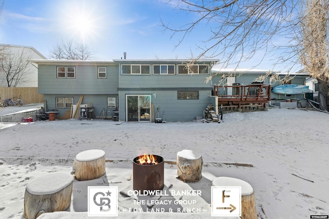 snow covered rear of property featuring a wooden deck and a fire pit