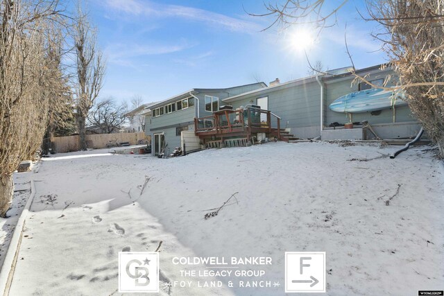 snow covered back of property with a deck